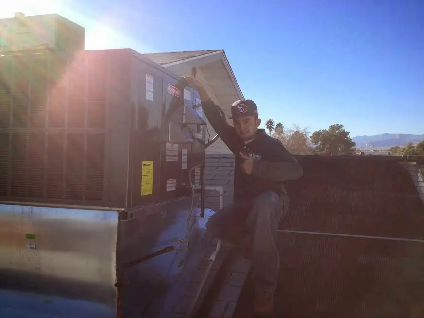HVAC technician performing AC Tune-Up on a rooftop unit in Acton